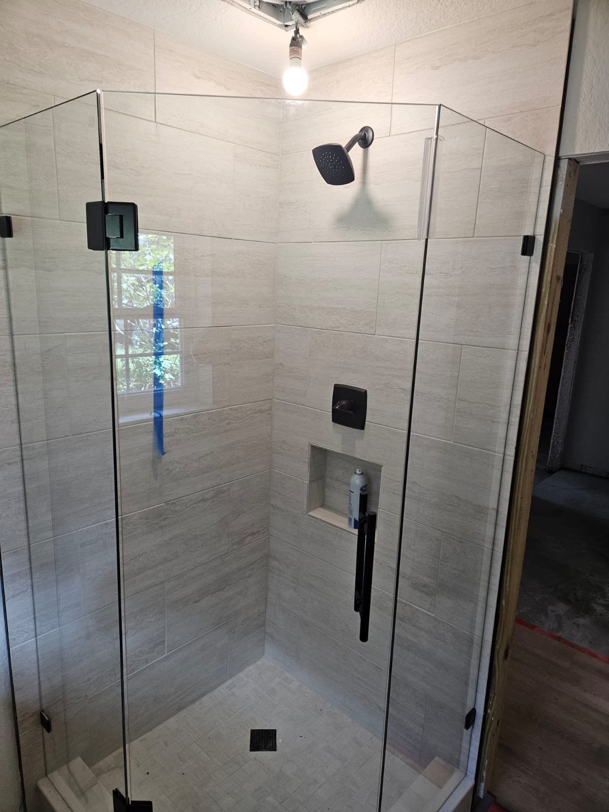 Glas Plus 135° neo-angle bathroom example WITHOUT transom: the glass door goes all the way up, with no fixed panel above it, with black hardware