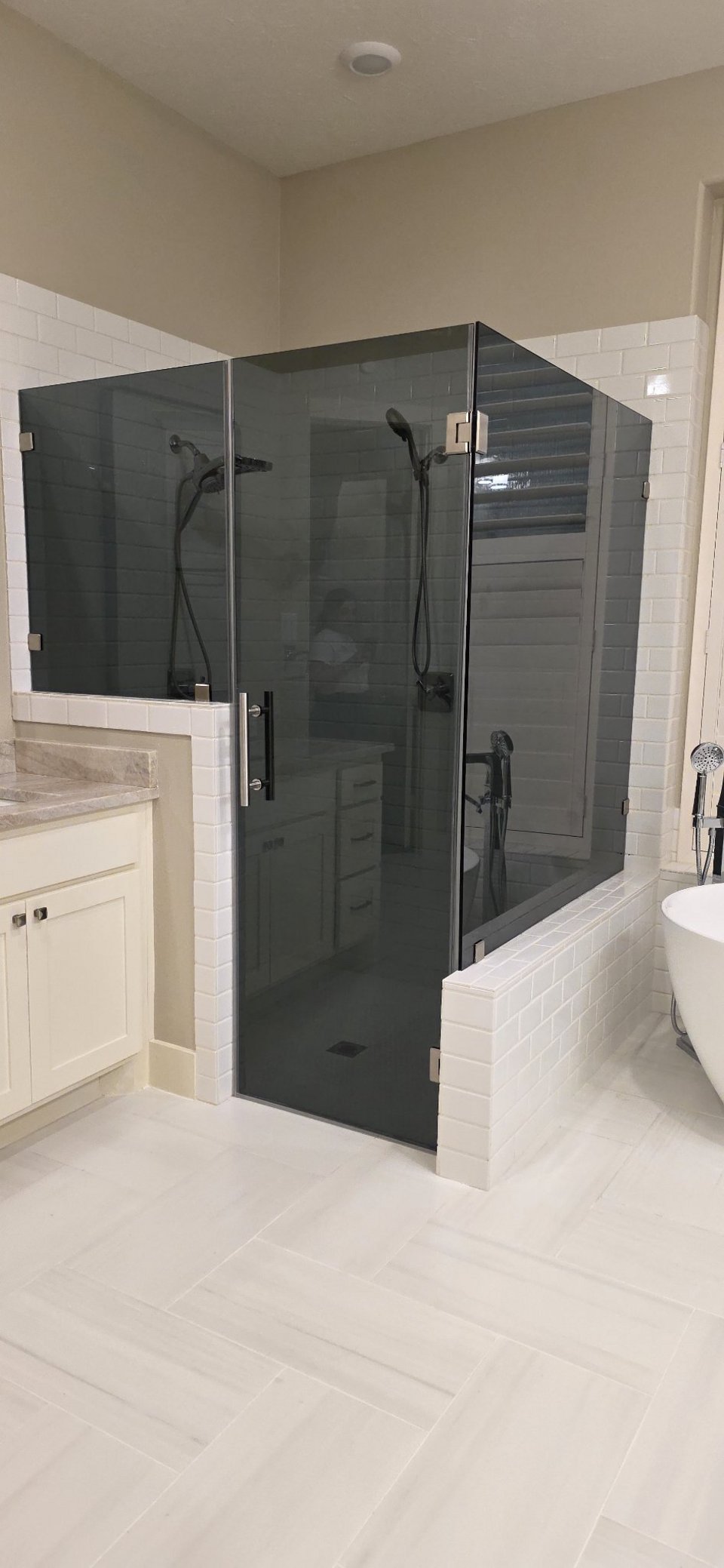 Glas Plus 90° angle over half walls example: grey glass mounted on white tile half walls, with a tub beside it