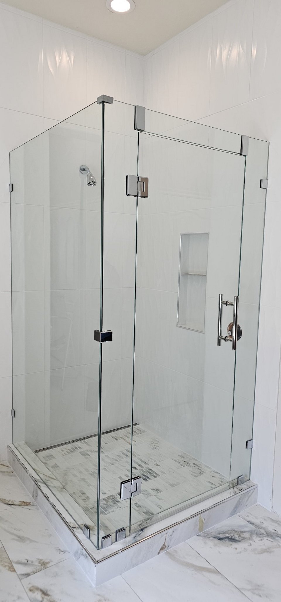 Glas Plus 90° angle over half walls example: clear glass with chrome hardware in a white tile 90° corner