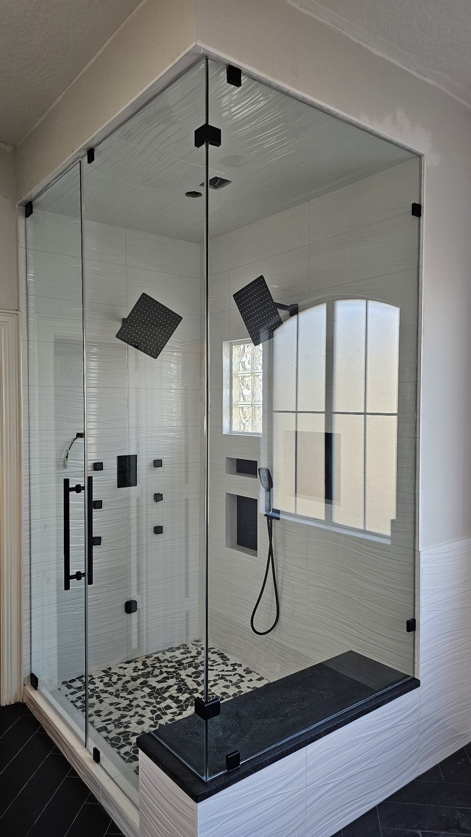 Glas Plus 90° angle over half walls example: clear glass with black hardware, with one panel mounted on a half wall used as a bench