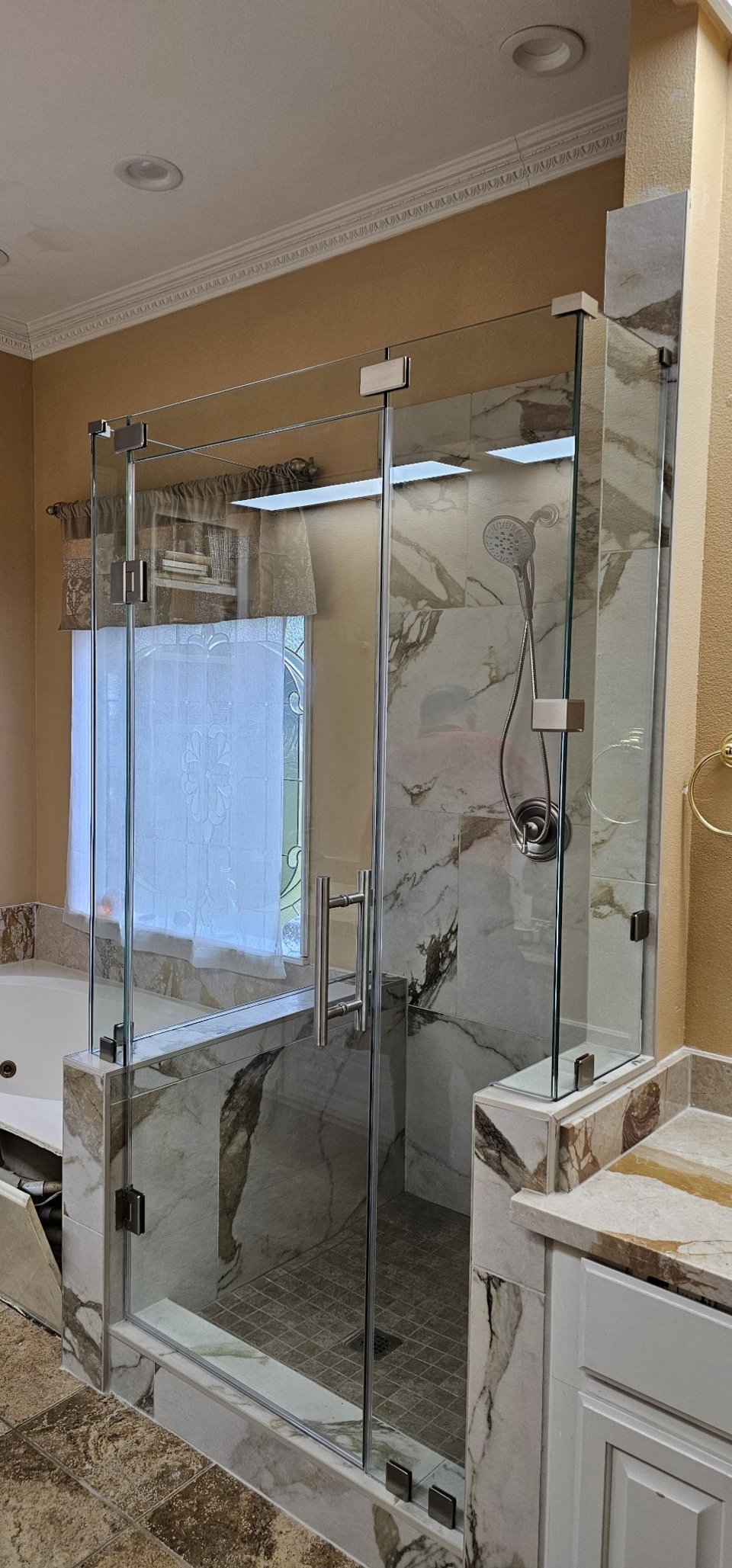 Glas Plus 90° angle over half walls example: clear glass with nickel hardware mounted on marble half walls, next to a tub