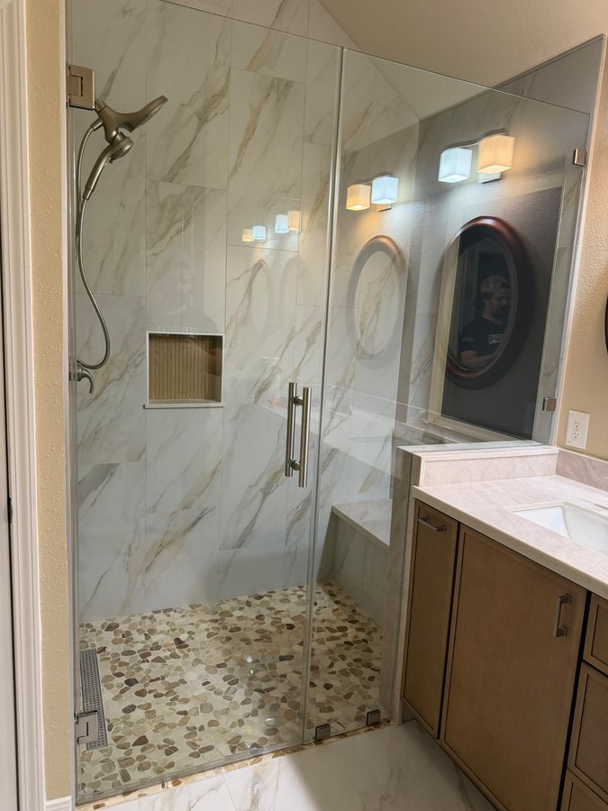 Glas Plus hinged door with wall example: wall-hinged door and fixed panel resting on the half wall next to the vanity, brushed nickel hardware