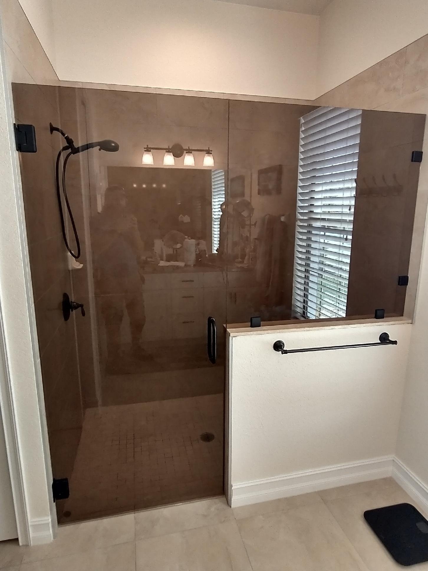 Glas Plus job: hinged door with Bronze glass (bronze tone), fixed panel over a half wall and black hardware