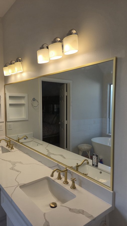 Glas Plus mirrors example: large vanity mirror with a gold metal frame over a marble double vanity