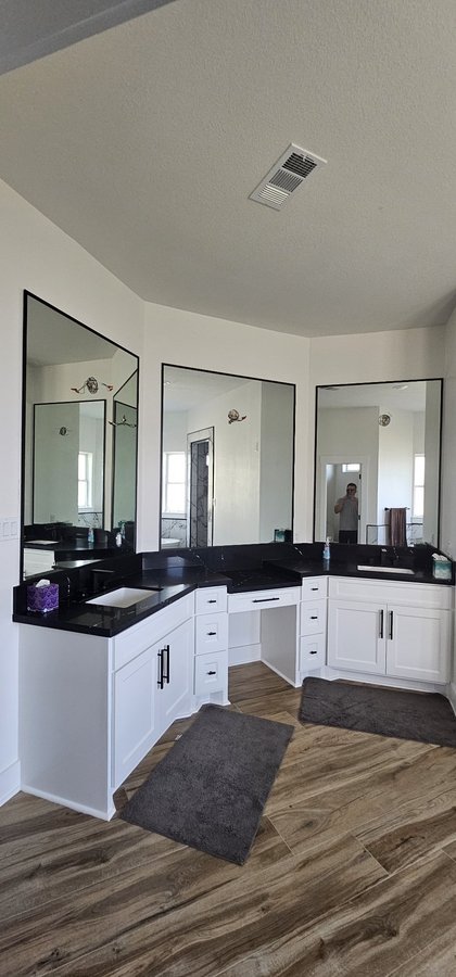 Glas Plus mirrors example: three mirrors with black metal frames in a bathroom with white vanities