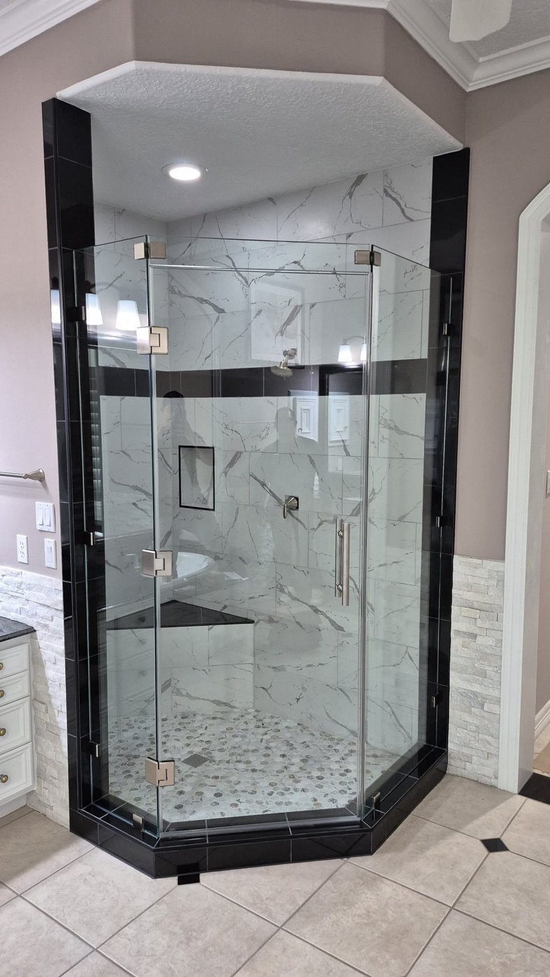 Glas Plus job: 135° neo-angle with brushed nickel hardware in a marble-look tile shower with a black band