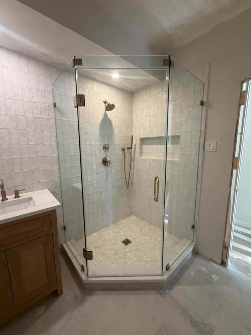 Glas Plus job: 135° neo-angle with gold hardware in a white tile shower