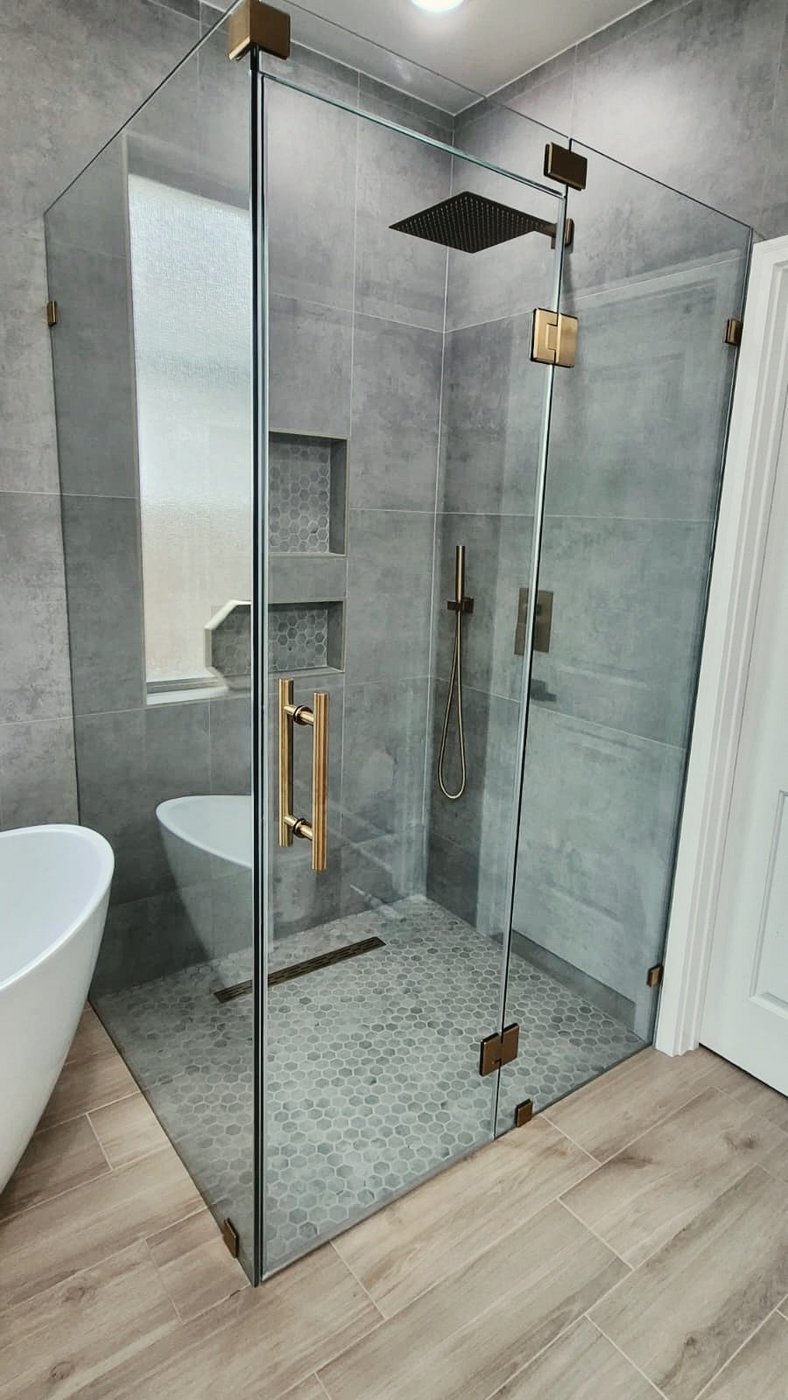 Glas Plus job: 90° angle with gold hardware in a grey tile bathroom
