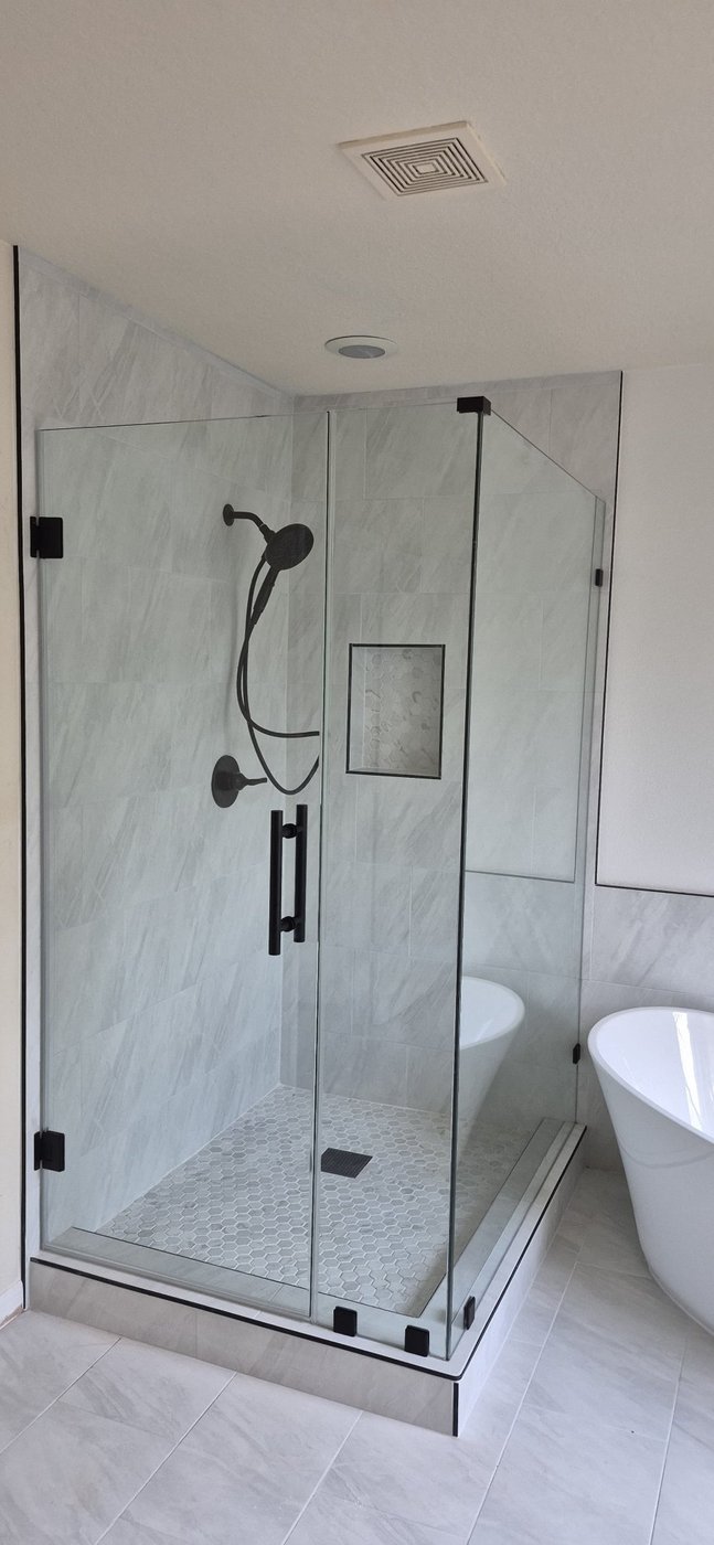 Glas Plus job: 90° angle with black hardware in a light marble bathroom
