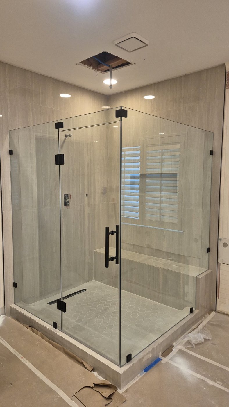 Glas Plus job: 90° glass-to-glass angle with black hardware and a bench inside the shower
