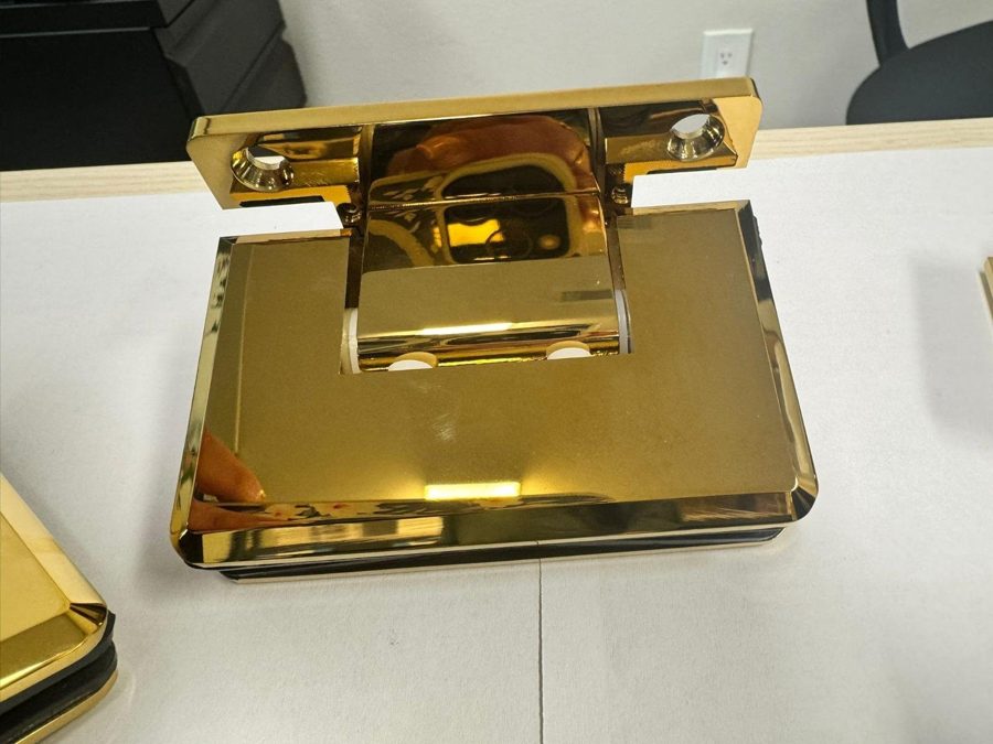 Glas Plus polished gold hinge seen from the front on a white table