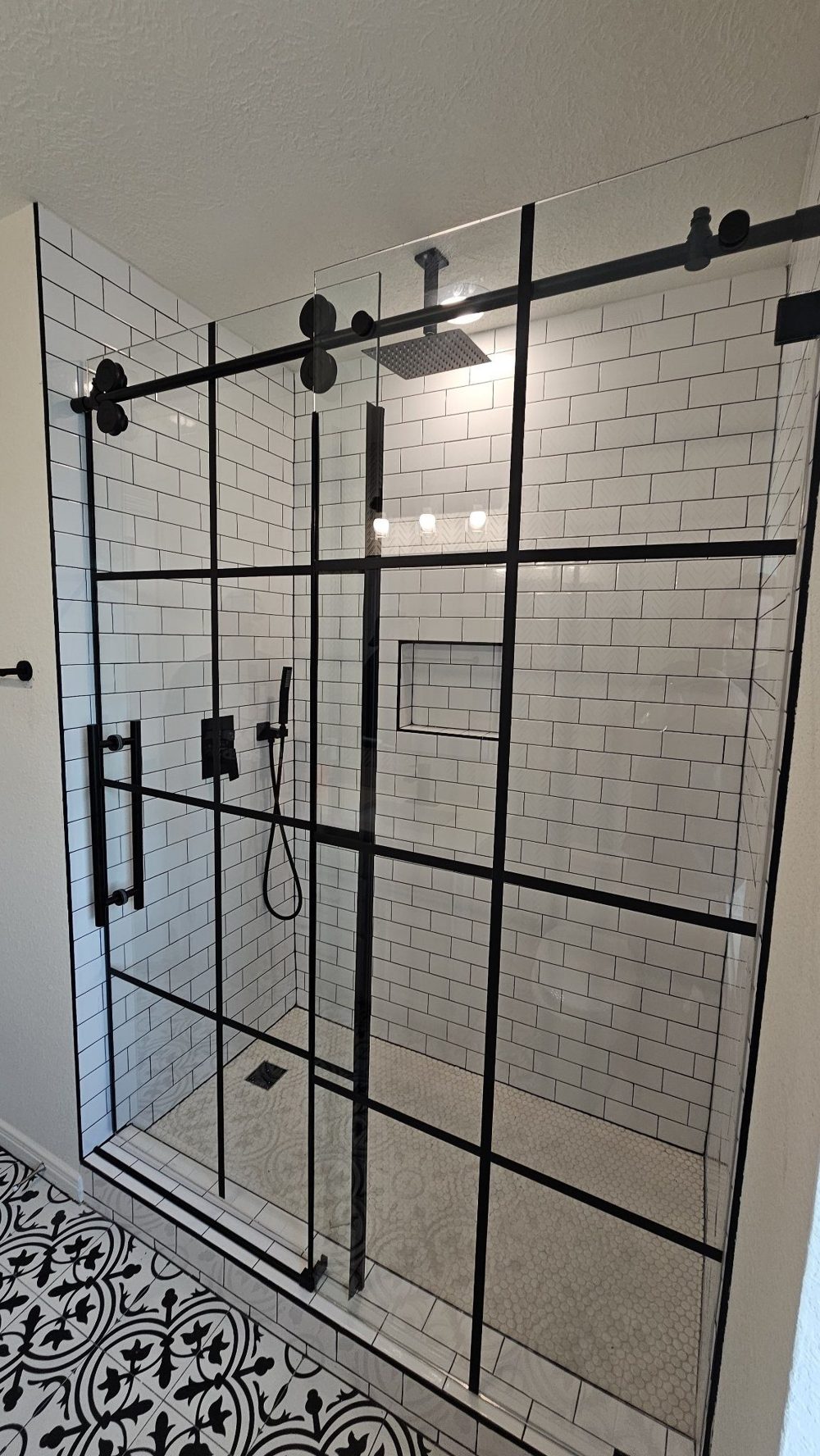 Glas Plus job: one-door sliding with fixed panel, industrial style with black frame and grid, in a white subway tile shower