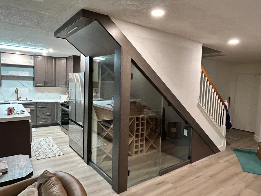 Glas Plus special orders example: glass wine cellar under the stairs with a dark frame, next to the kitchen