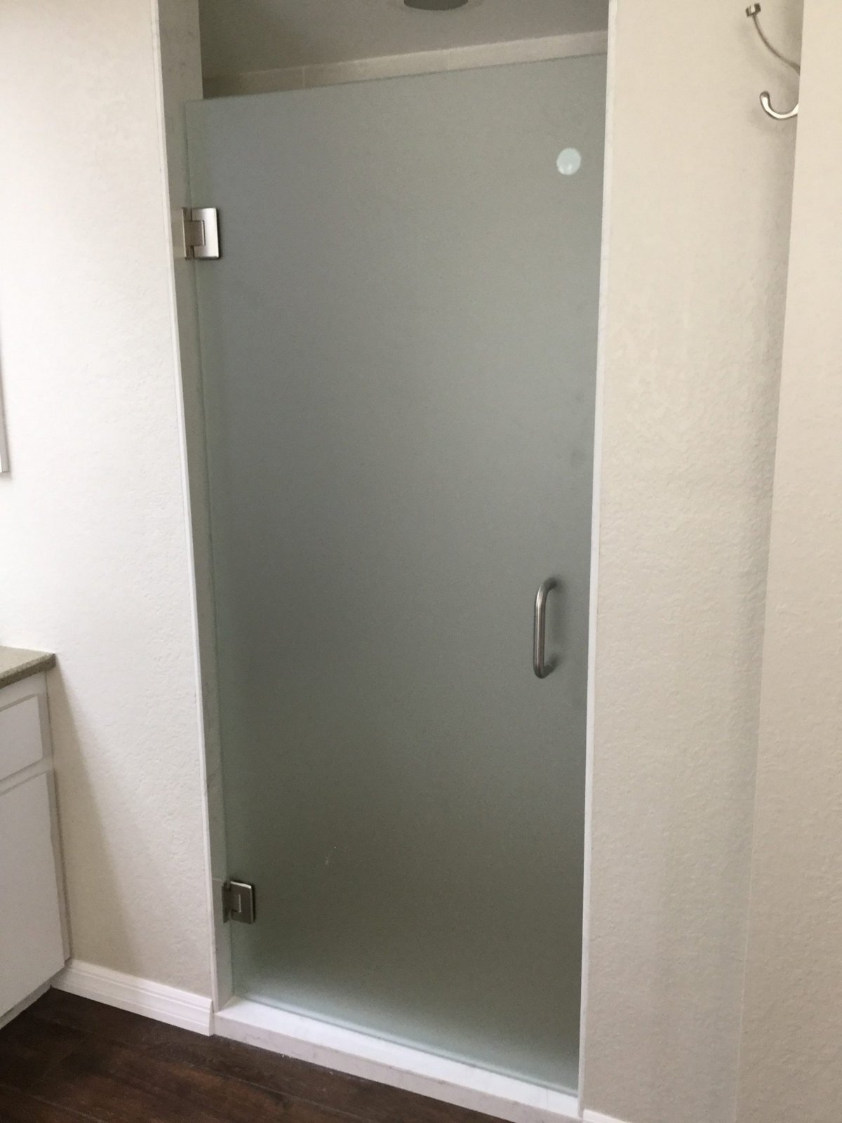 Single door with Frosted glass (privacy) and brush nickel hardware installed by Glas Plus in a white-walled shower