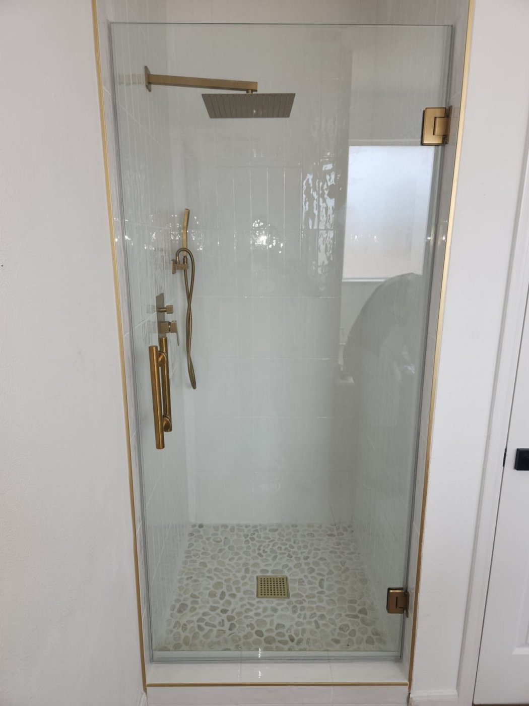Single door with brush gold hardware installed by Glas Plus in a white tile shower