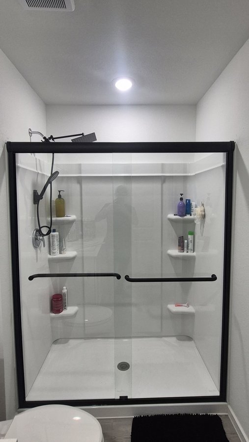 Double-door sliding with a full black frame in a grey shower with a niche