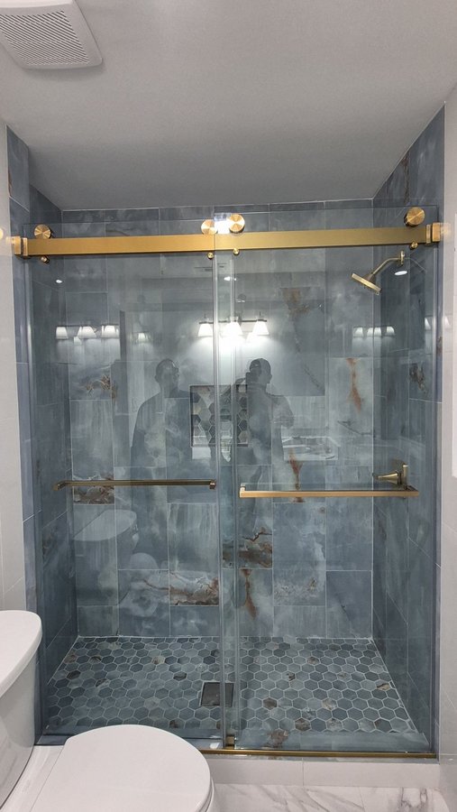 Double-door sliding with gold track in a white tile shower with a niche