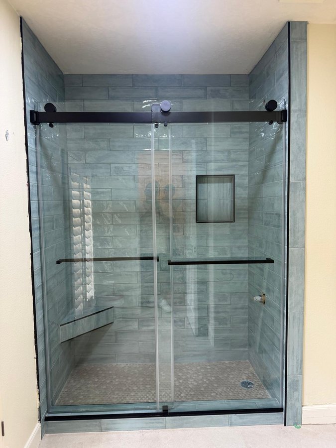 Double-door sliding with black track in a marble tile shower with a niche