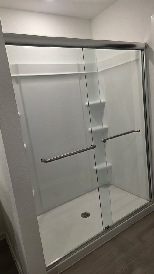 Double-door sliding with nickel hardware in a white shower with a bench