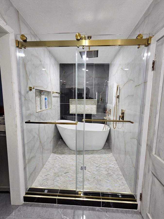 Double-door sliding with gold track in a large light tile shower