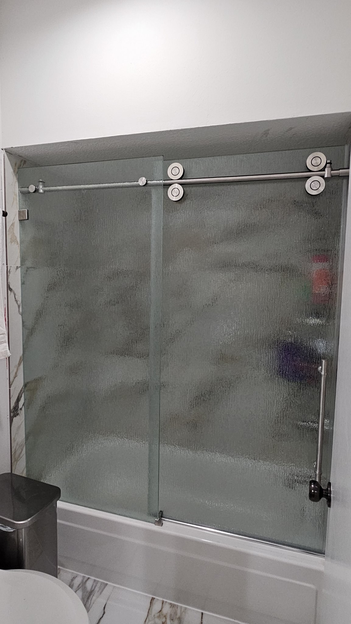One-door sliding with Rain glass (rain texture) and brushed nickel track over a tub