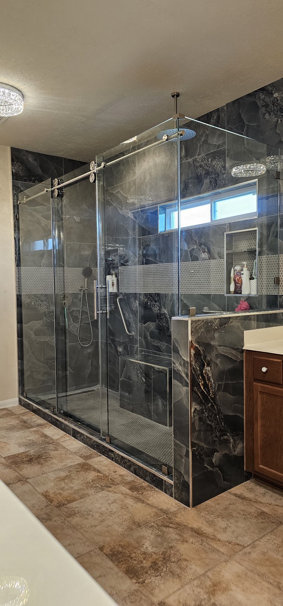 Glas Plus one-door sliding with fixed panel example: sliding glass door on a chrome track next to a fixed panel, in a large dark marble bathroom