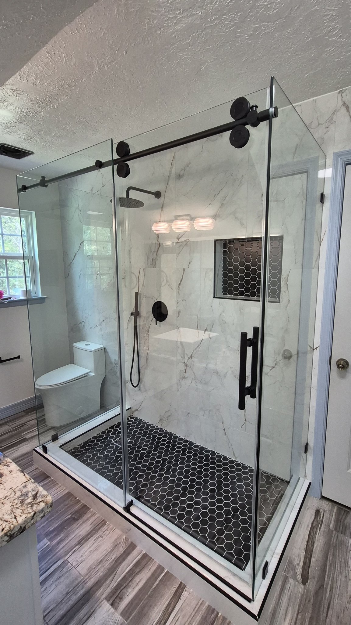 Sliding with return with a black track in a marble shower with a hexagonal floor and niche