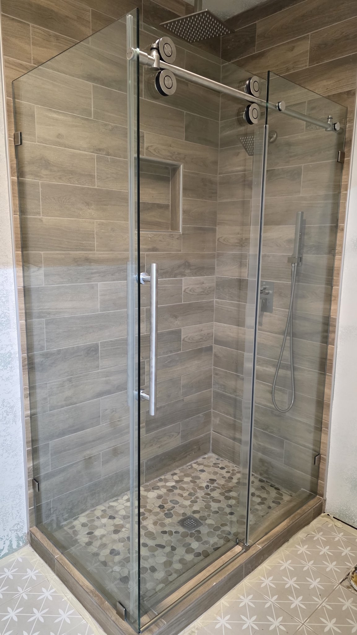 Sliding with return with a brush nickel track in a wood-look tile shower with a niche