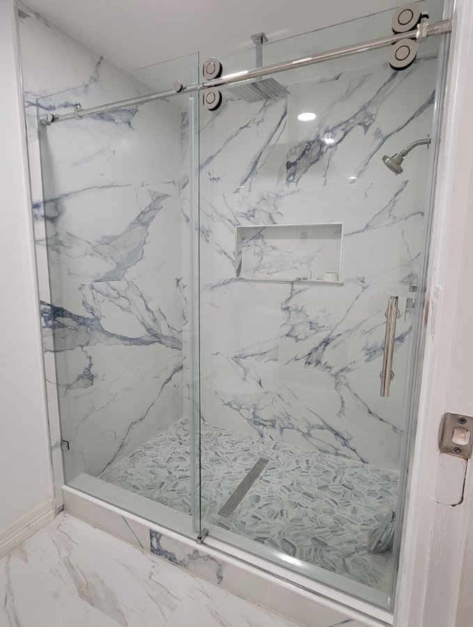 One-door sliding with chrome track and fixed panel in a white marble shower