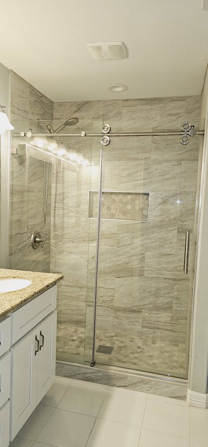 One-door sliding with chrome track and towel bar in a marble tile shower