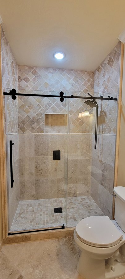 One-door sliding with black track and fixed panel in a light tile shower